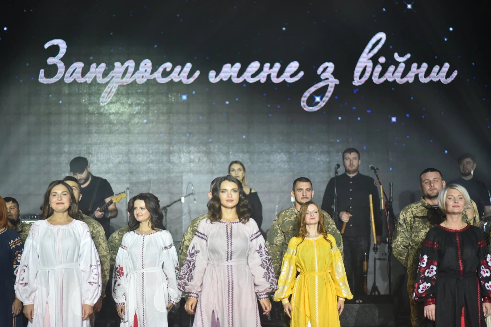 Performers in embroidered dresses on stage at the Invite Me Out of the War concert