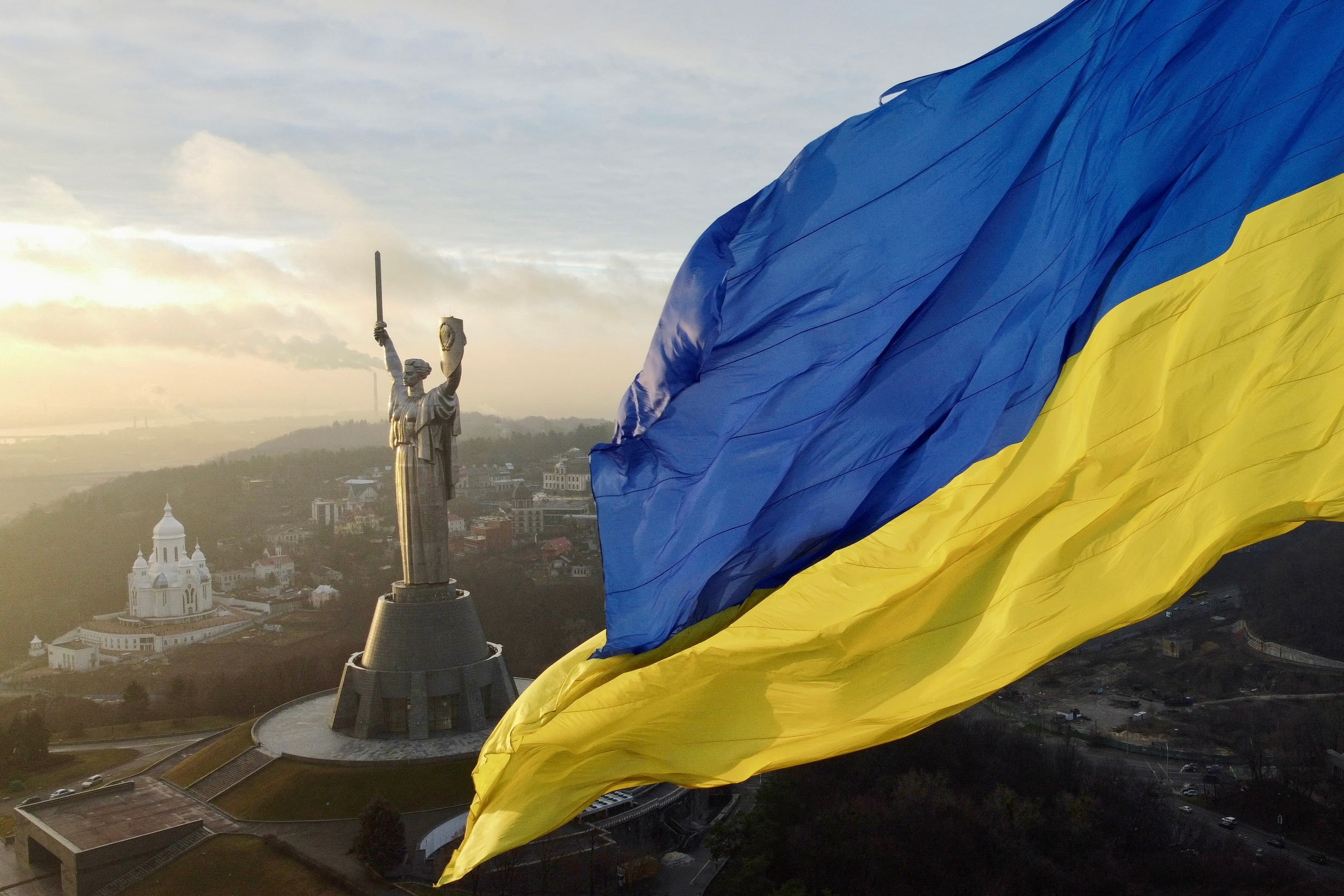 Ukrainian flag flying over the Motherland Monument in Kyiv at dawn